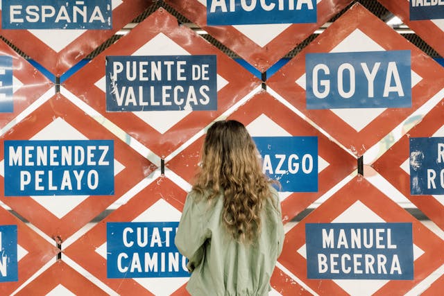 Una mujer delante de una pared decorada con varias placas de estaciones del Metro de Madrid